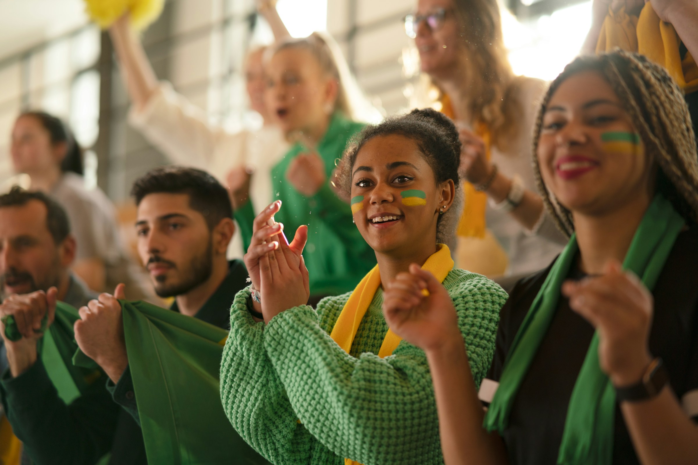 Diverse group of soccer fans celebrating together at a watch party, faces painted, cheering